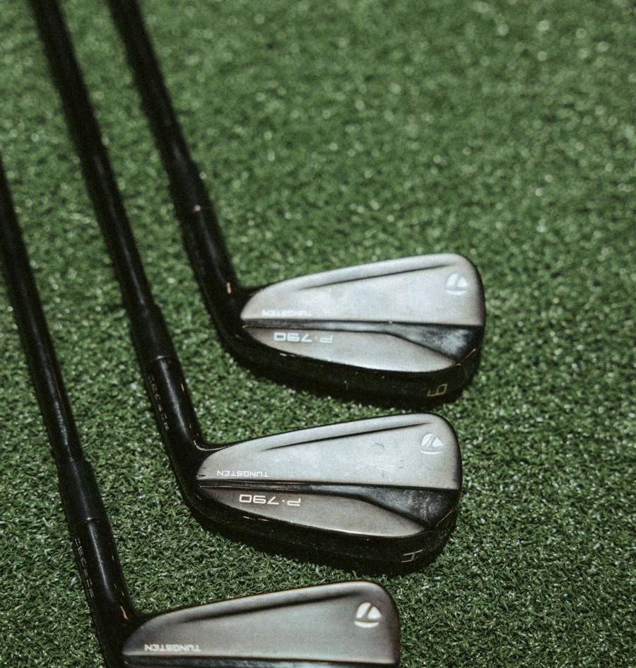 A set of irons laid out on hitting turf.