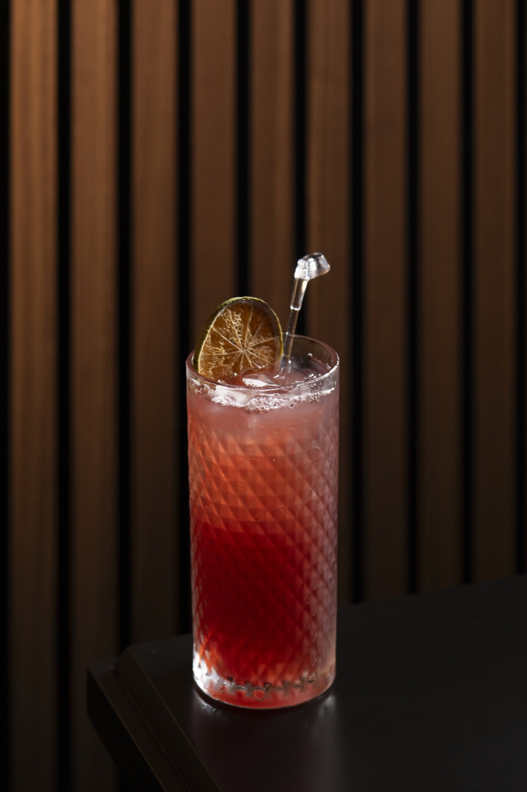 A red cocktail with a dried lime wheel on the bar at The Tips