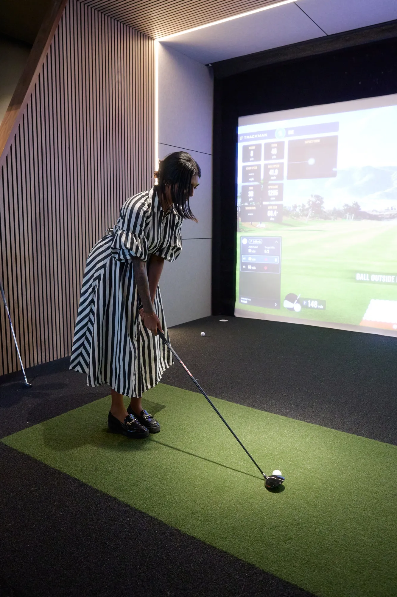 Golfer on the hitting mat facing the Trackman screen