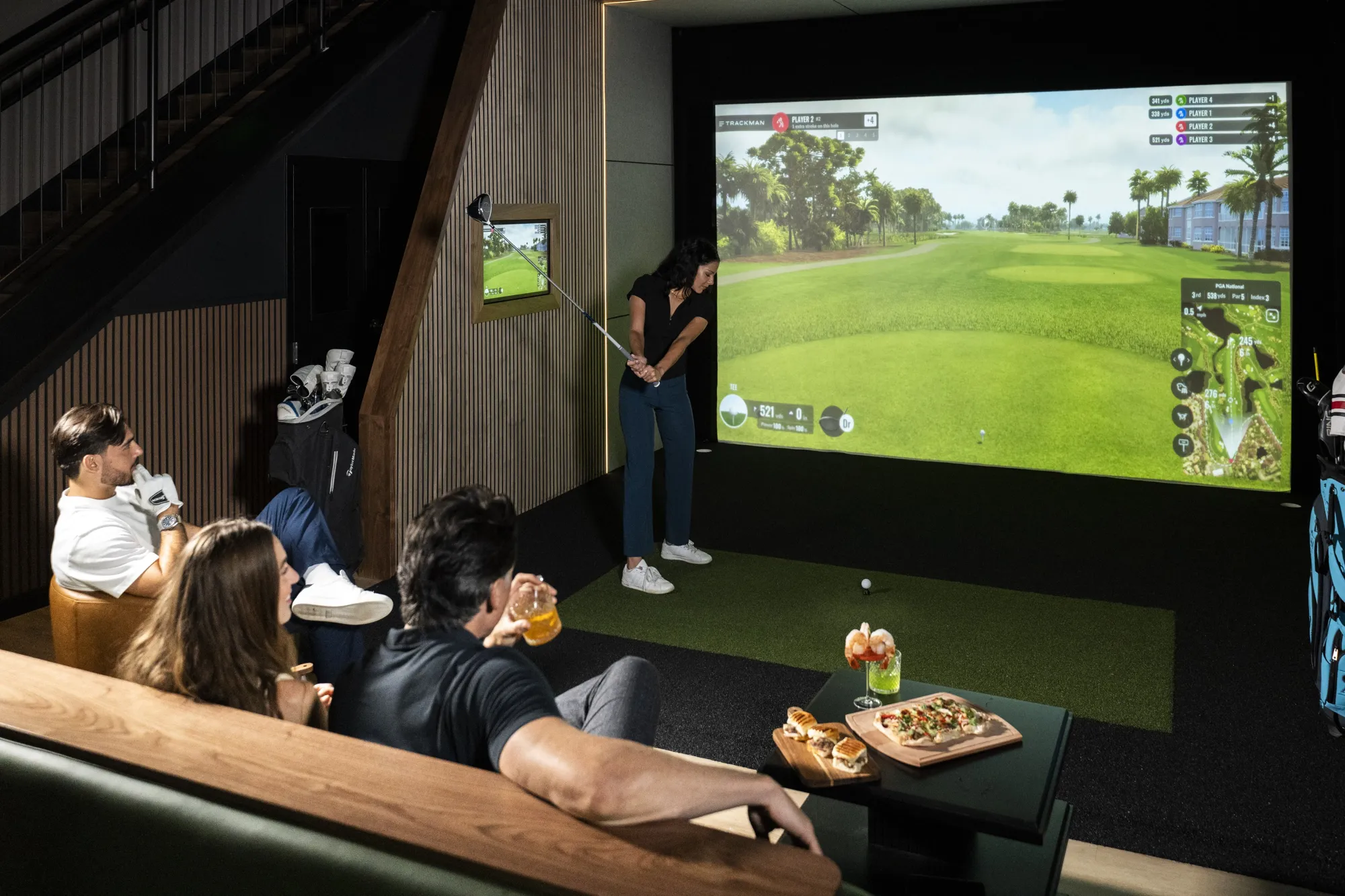 Golfer swinging while friends watch from the couch