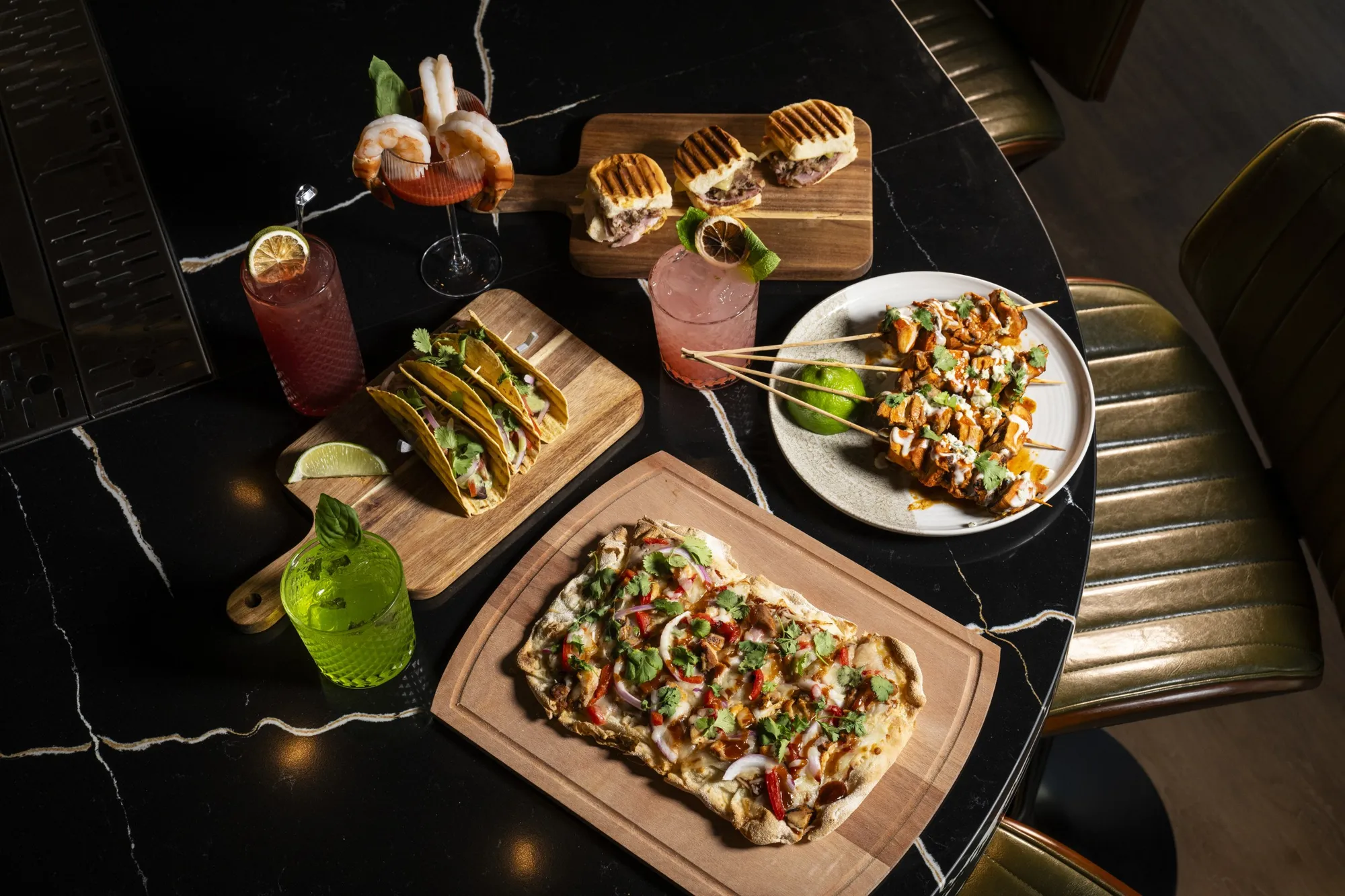 Tacos, sliders, flatbread and cocktails on a bay table