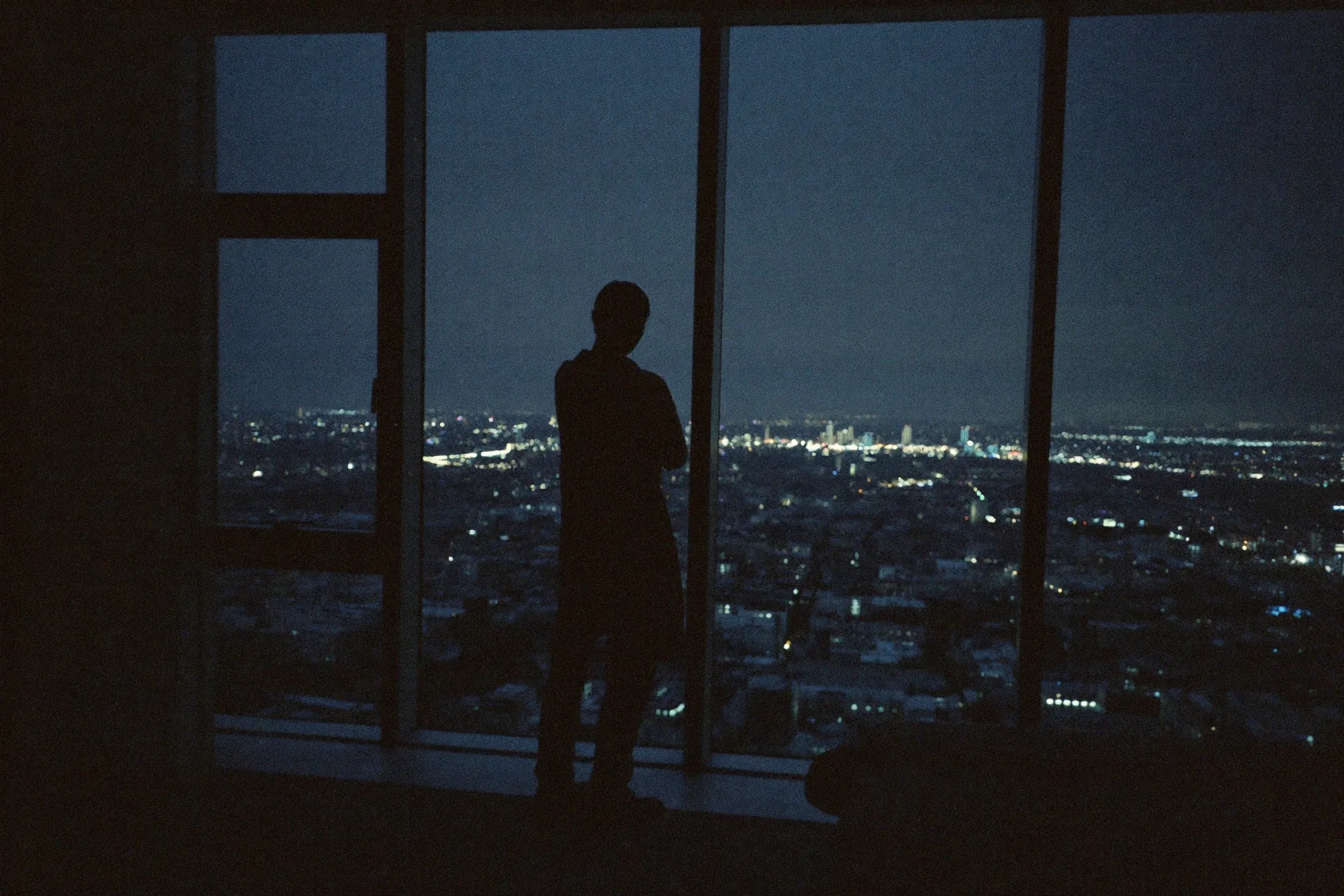 Founder at a window overlooking a dark city at night