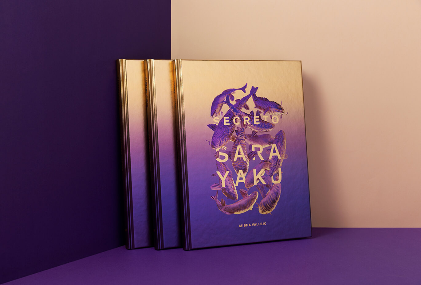 Editorial book cover design for “Secreto Sarayaku” displayed on a purple and beige set, featuring illustrated fish and gold typography.
