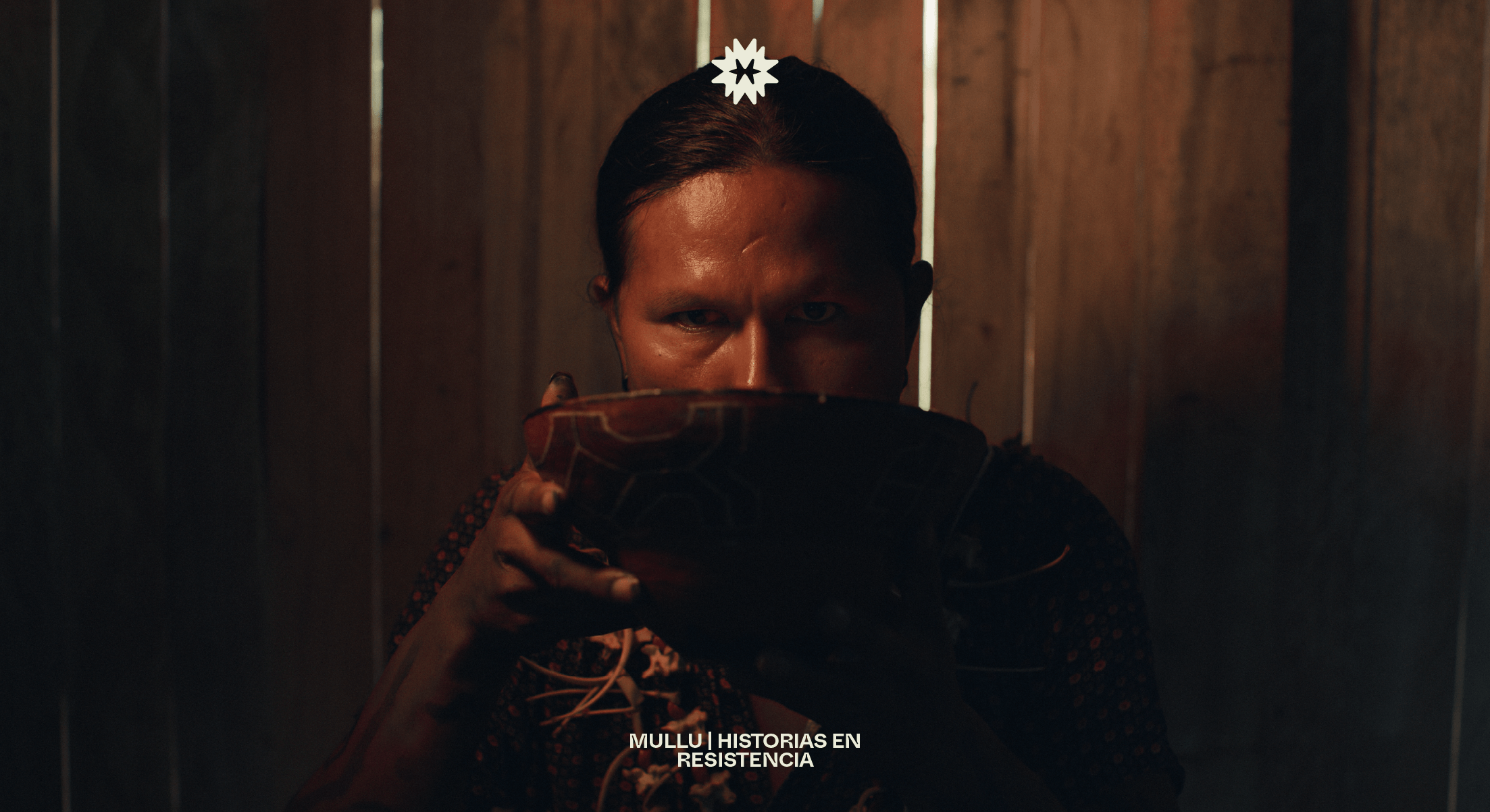 Cinematic portrait for Mullu by Lunalunares, featuring a person holding a vessel in low light, with the Mullu symbol applied above as part of the identity system.