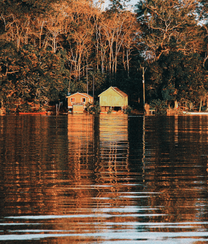 River territory photography for the Mullu branding project by Lunalunares, showing houses by the water, forest reflections, and a warm documentary atmosphere.