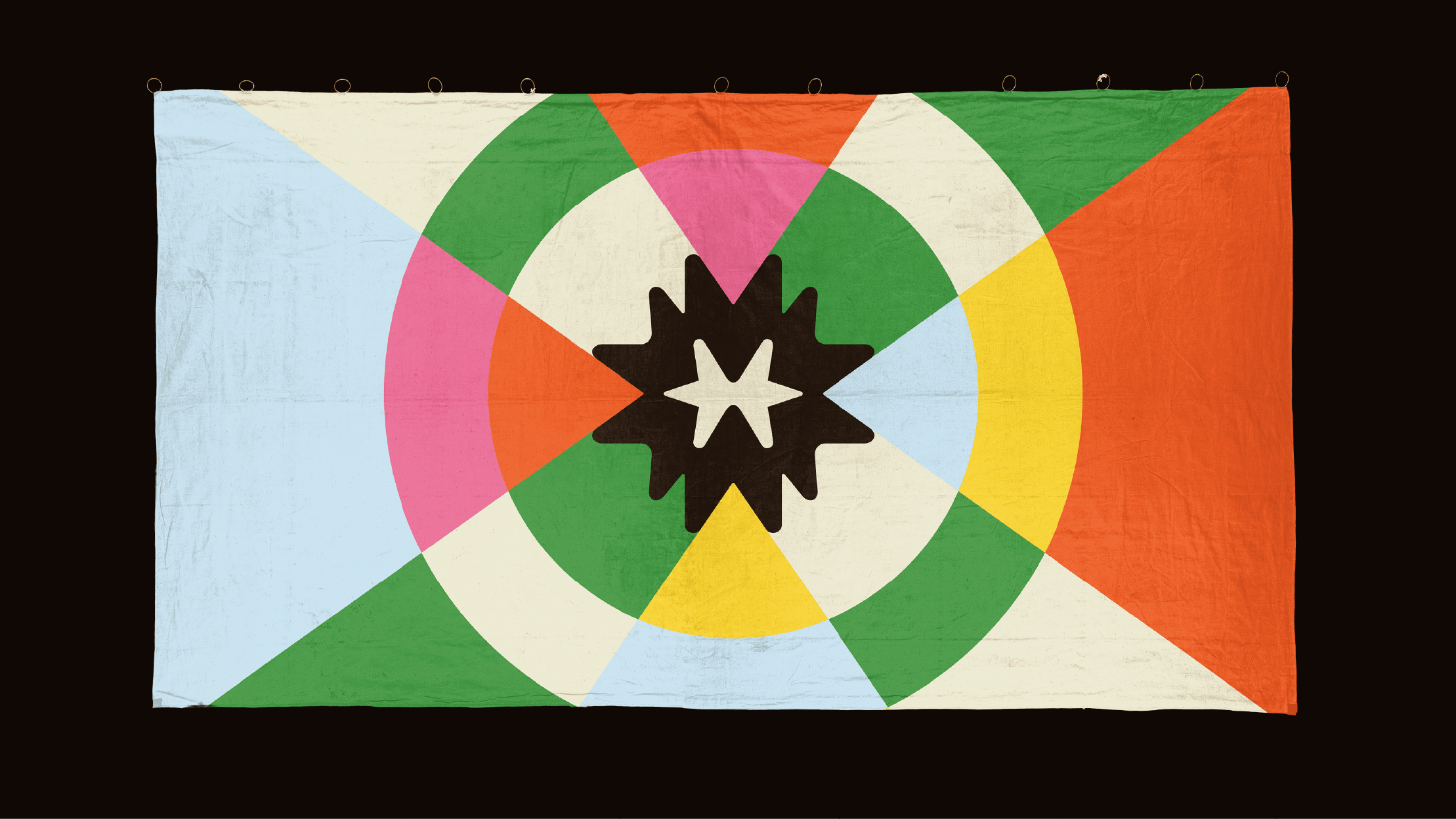 Mullu flag design by Lunalunares, featuring a colorful geometric textile composition with green, orange, yellow, blue, pink, cream, and a central star symbol.