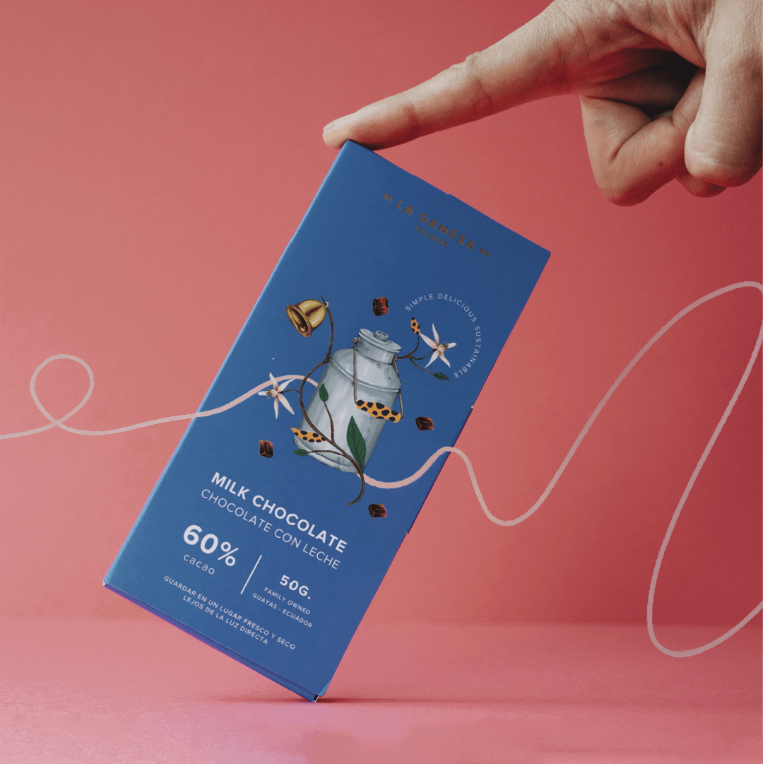 Milk chocolate bar packaging design for La Danesa by Lunalunares, featuring a blue box with botanical illustration, chocolate details, brand seal, and playful product photography composition.