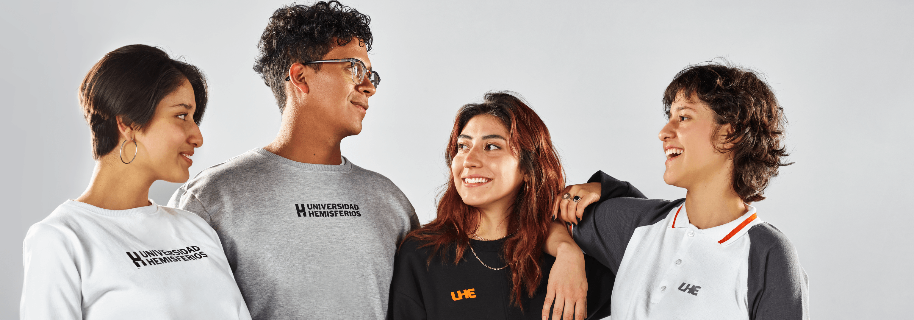 Student apparel branding for Universidad de los Hemisferios by Lunalunares, showing a group of students wearing institutional T-shirts, sweatshirts, and polo shirts with UHE logo applications.