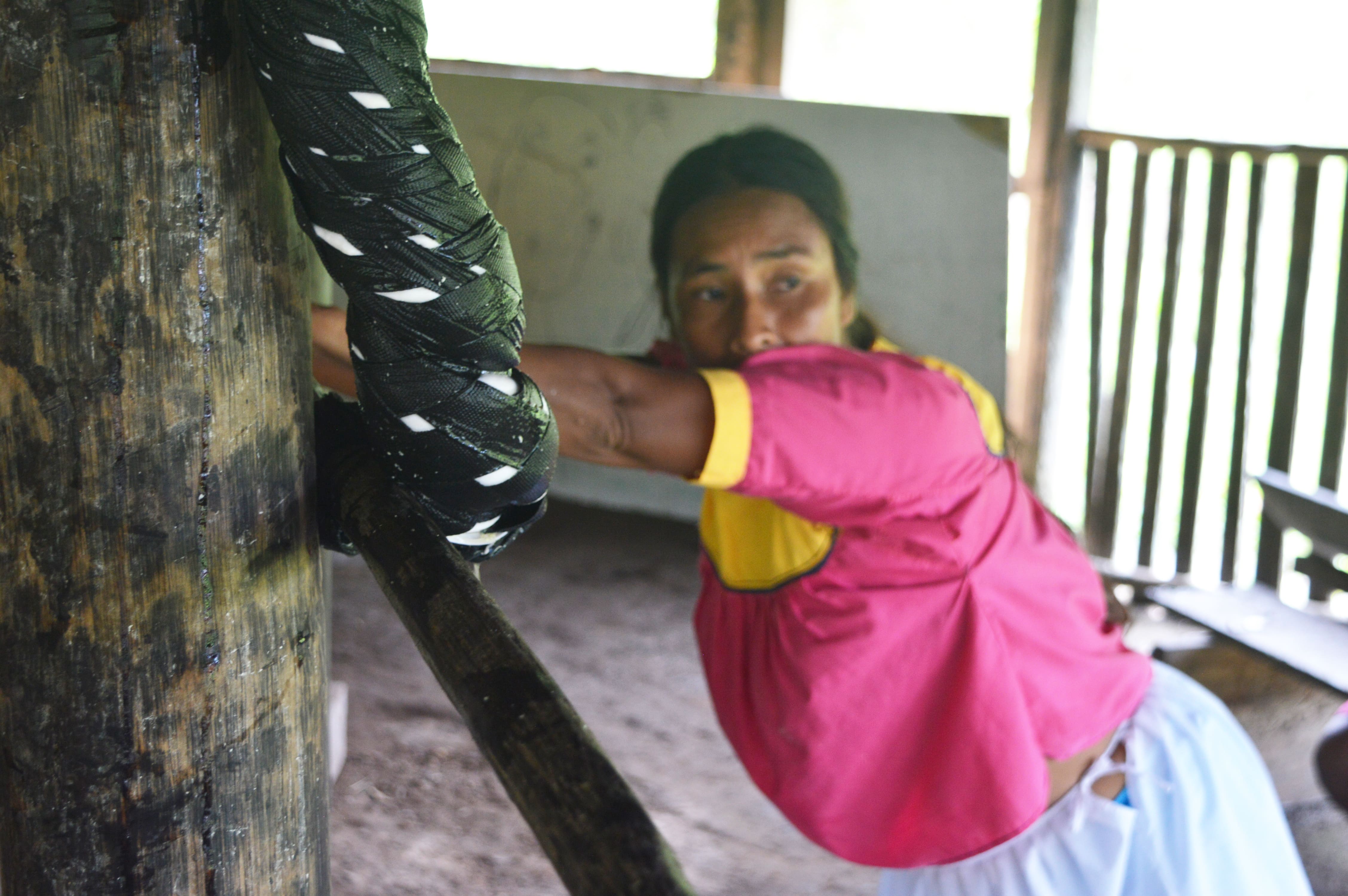 Artisanal Amazonian food processing for Canopy Bridge, showing a woman working manually in a rustic setting as part of the yuca preparation and fermentation process.