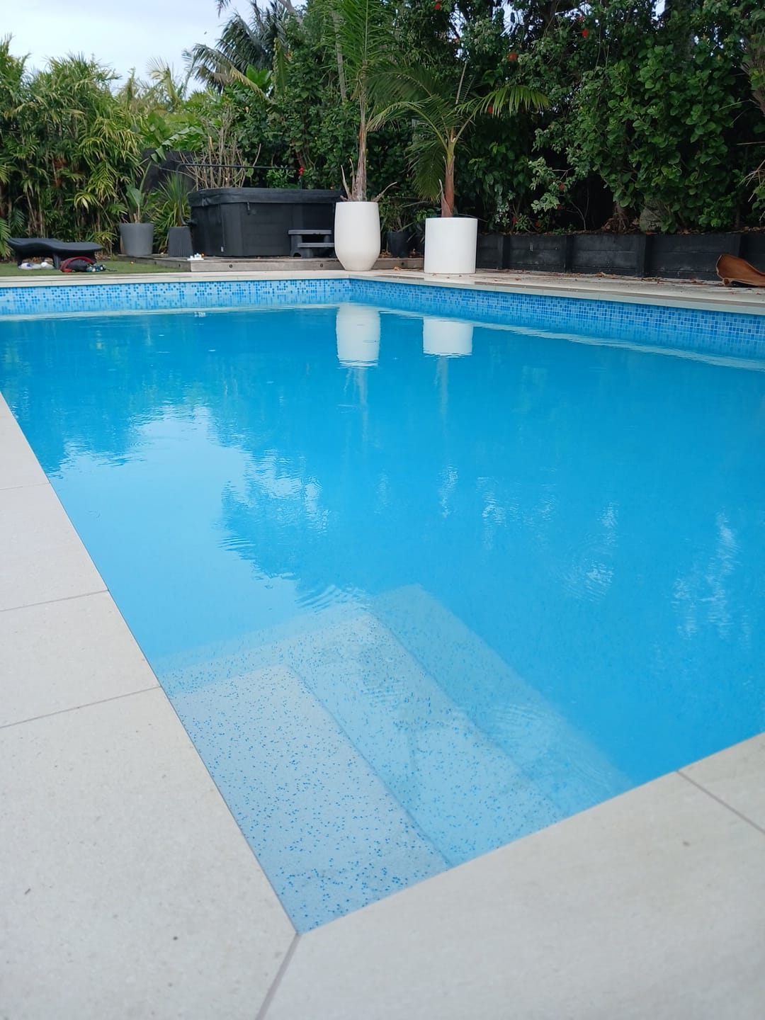 A complete swimming pool renovation featuring a premium aggregate resurfacing, new glass mosaic waterline tiles, and a fully retiled outdoor entertaining area, transforming a tired pool into a stunning backyard centrepiece.