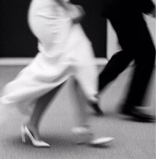 Black and white photo of a man and woman walking, showing only their legs in motion.