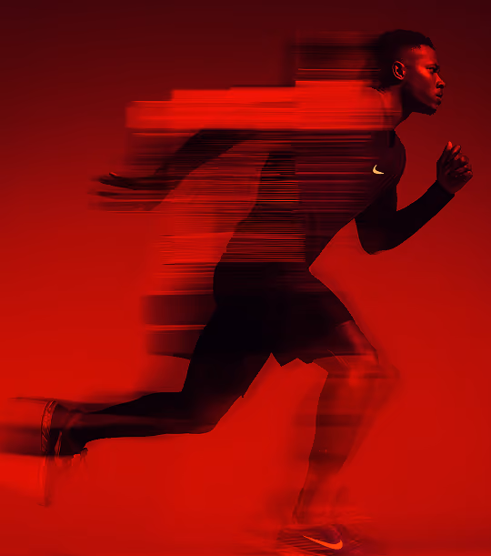 Male runner in Nike gear sprinting with motion blur effect on red background.