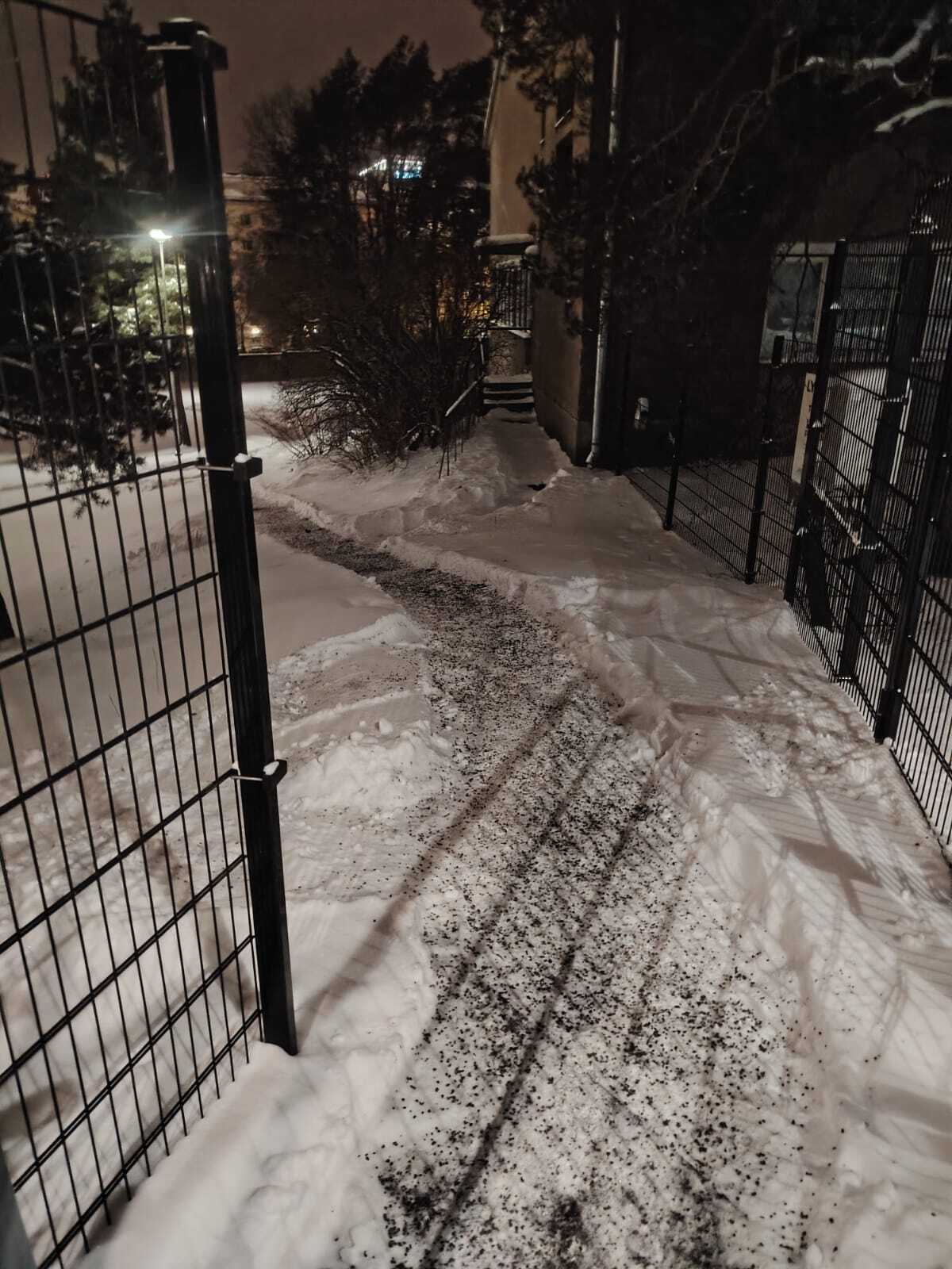 Lumesta aurattu ja hiekoitettu kulkuväylä taloyhtiön pihalla talvi-iltana.