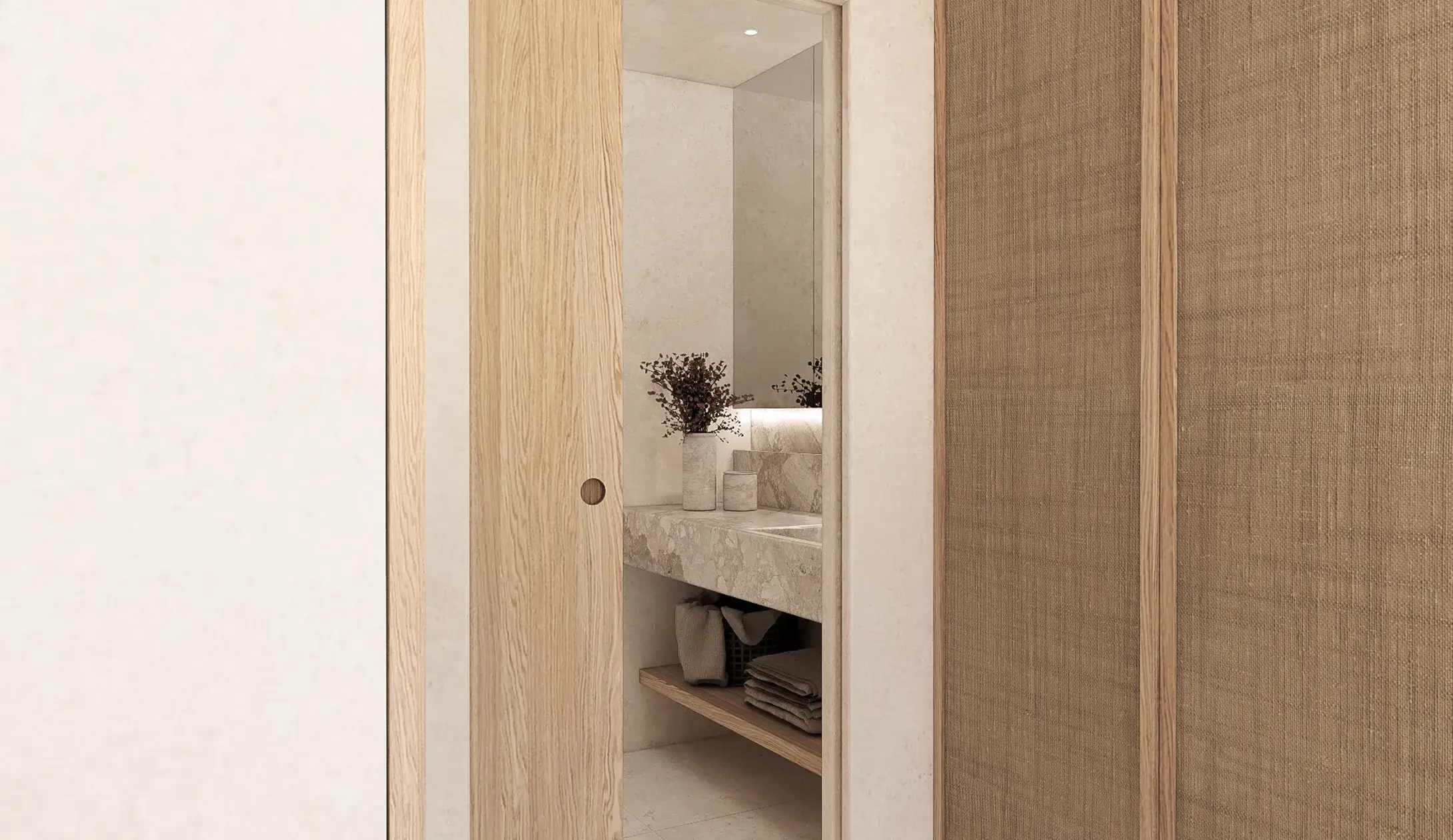 Elegant interior architecture at Can Lantana, Ibiza, featuring a wooden sliding door, woven wardrobe panels, and a marble bathroom vanity.