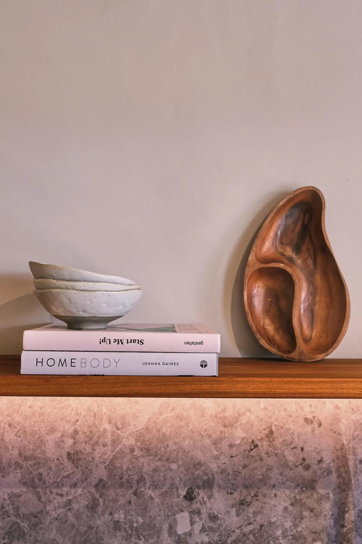 Interior design decor details at Sa Caleta, featuring design books, handmade ceramic bowls, and an organic wooden sculptural dish.