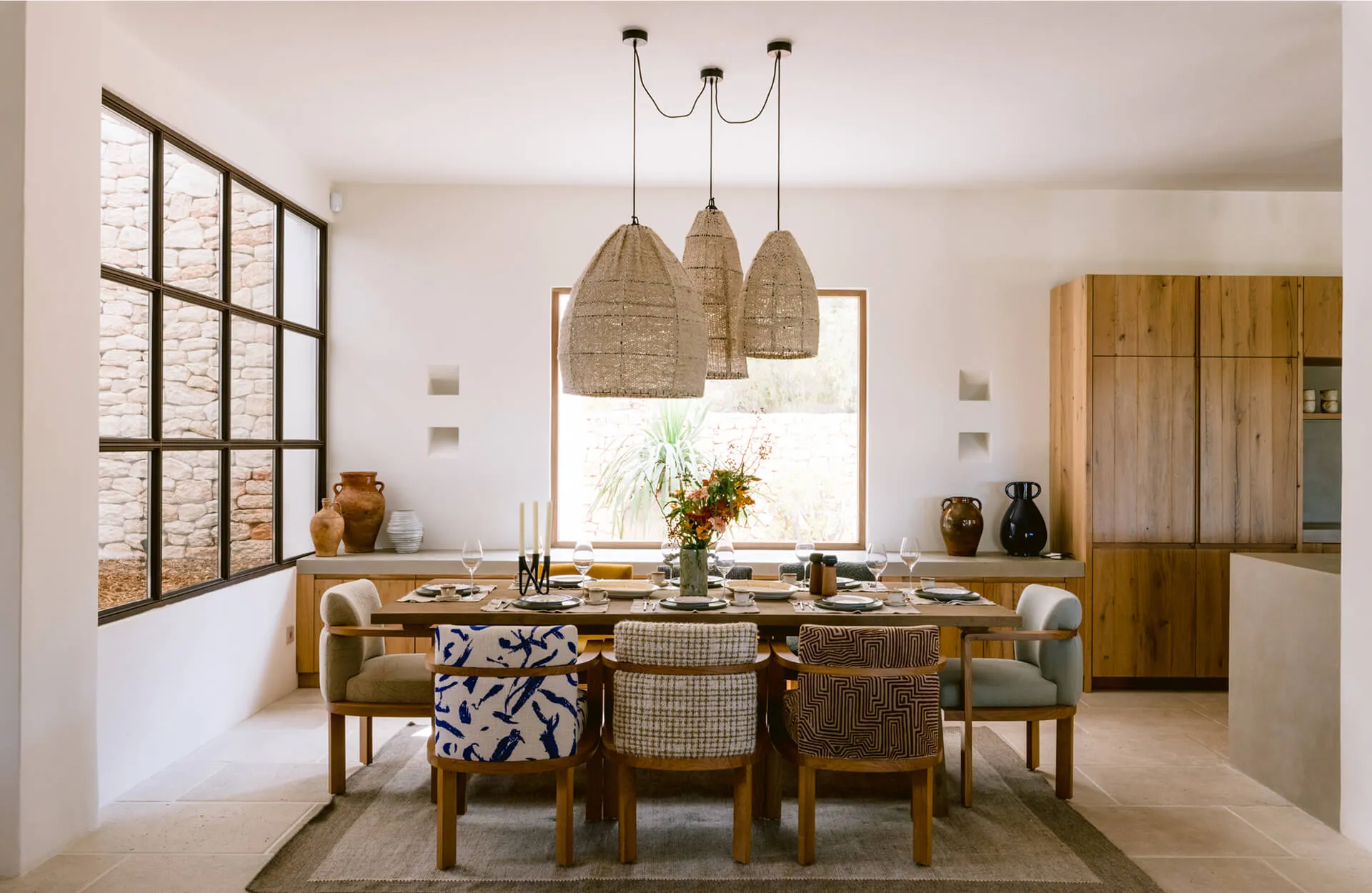 Exquisite dining room interior design at Villa Benimussa, Ibiza, highlighting custom upholstered pattern chairs and oversized woven pendant lights