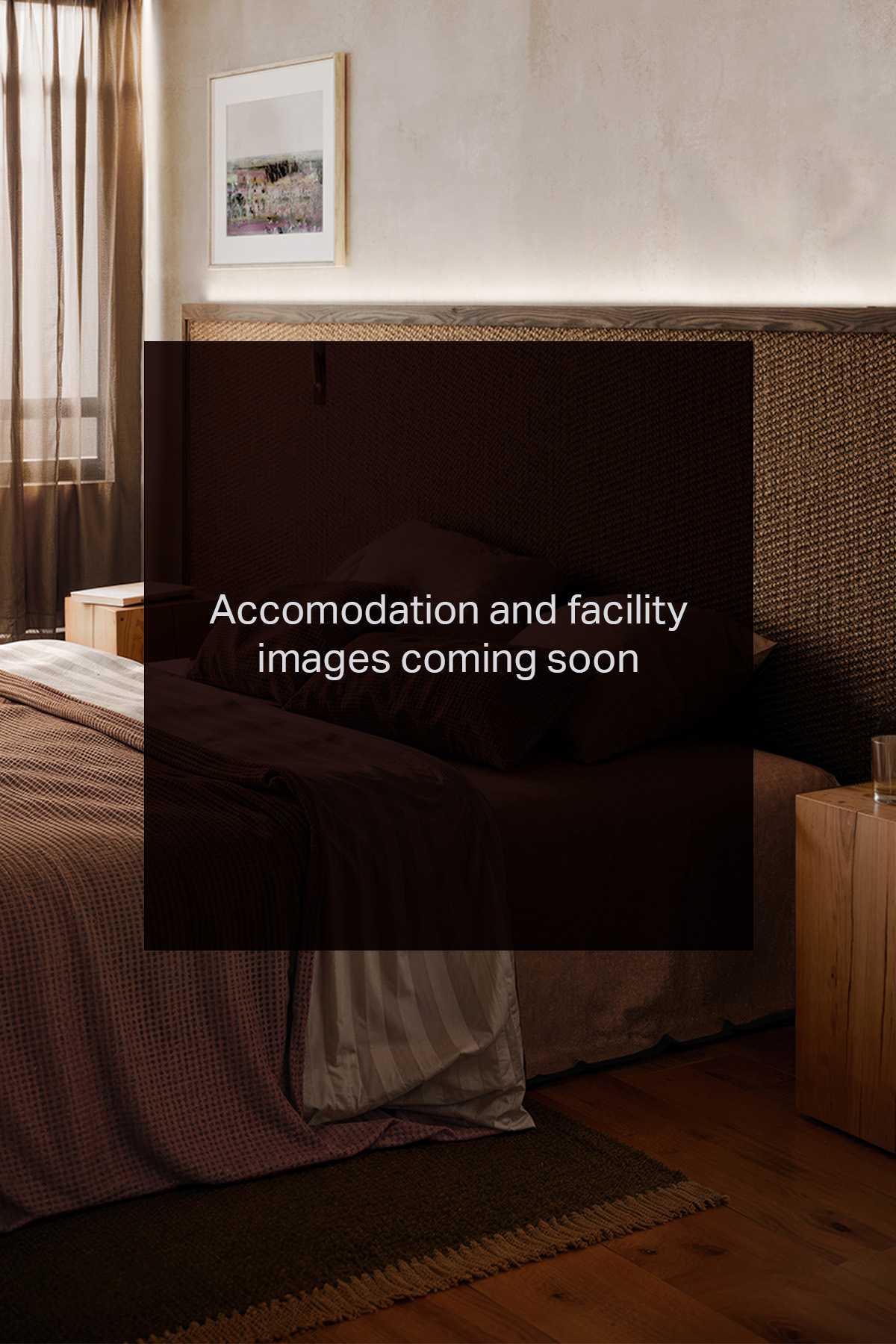 Cozy bedroom with textured headboard, soft bedding, wooden nightstand, and sheer curtains by a window.