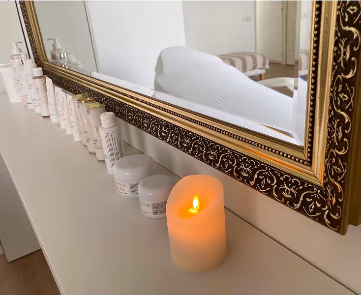 A picture about the decorative frame of the big mirror in the salon and a few jars of beauty products in front of it