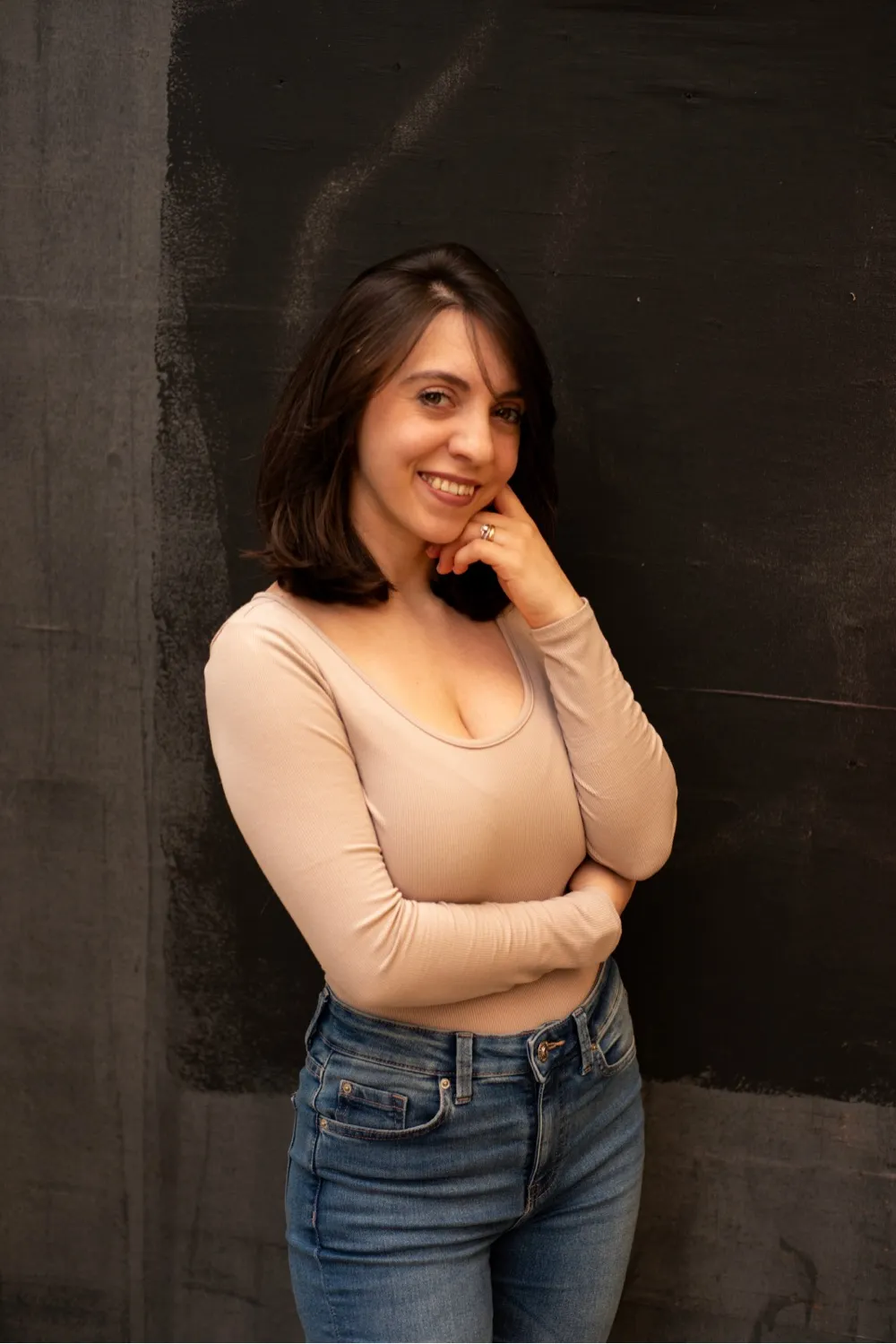 Clara Cristea, UX Designer, smiling and leaning against a dark painted wall