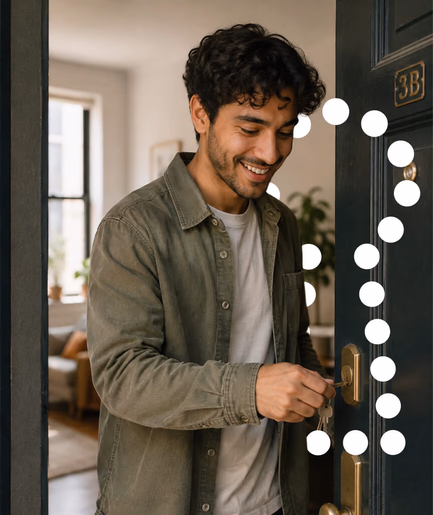 Smiling man unlocking the door to apartment 3B with a brass key.