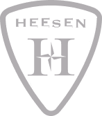 Shield emblem with abstract overlapping shapes forming a symmetric pattern inside. Heesen logo.