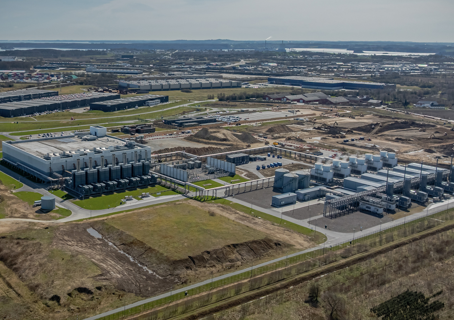 Aerial view of a large industrial campus with rows of buildings beside open land.
