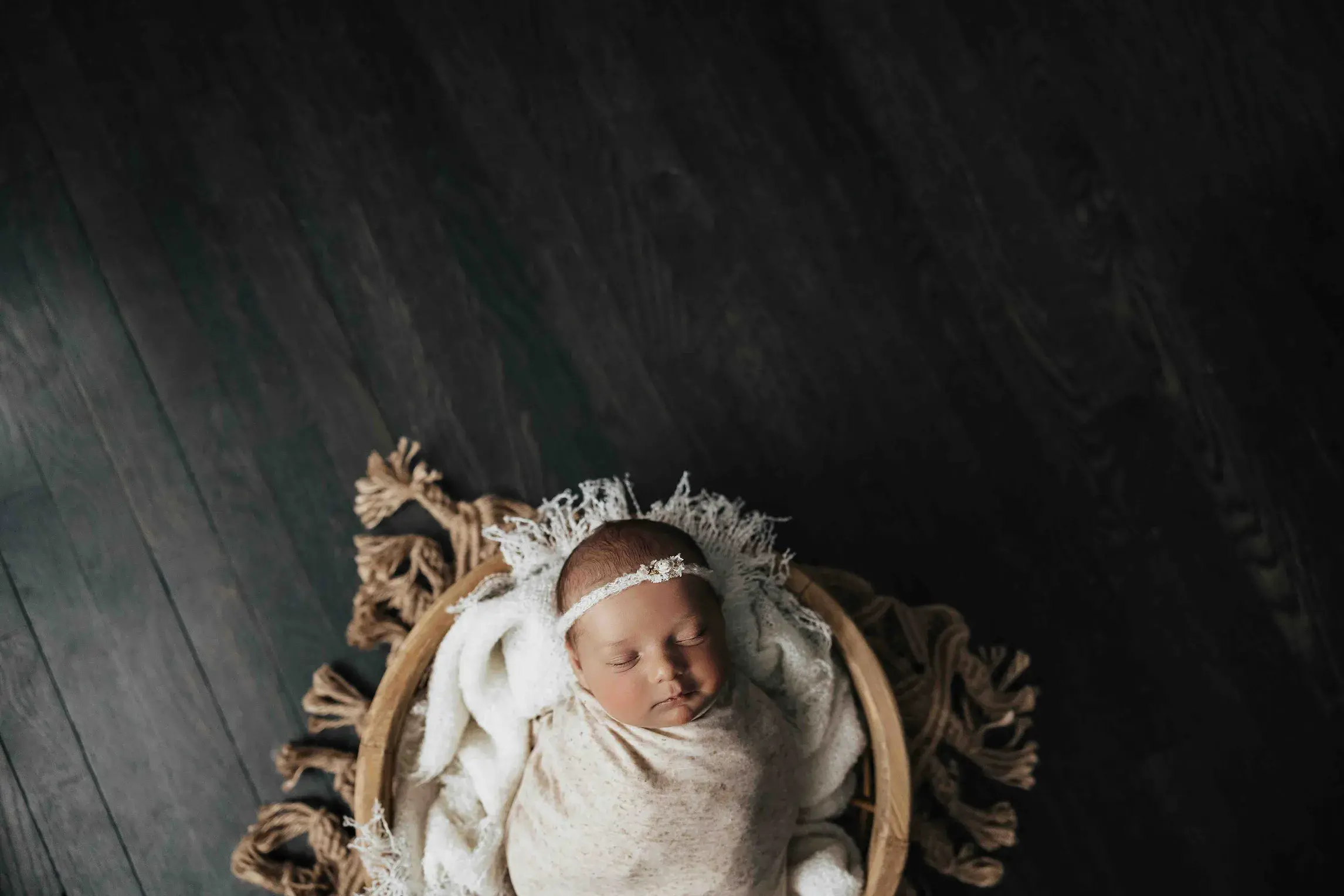 Sleeping newborn baby wrapped in a soft blanket and wearing a delicate headband, photographed in a cozy newborn setting in Springfield, Wilbraham, Massachusetts.