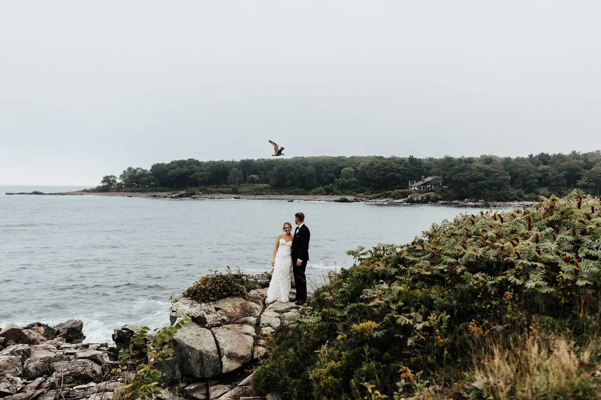 Bride and groom sharing a quiet moment on the rocky shoreline at Stage Neck Inn during their wedding in York, Maine.