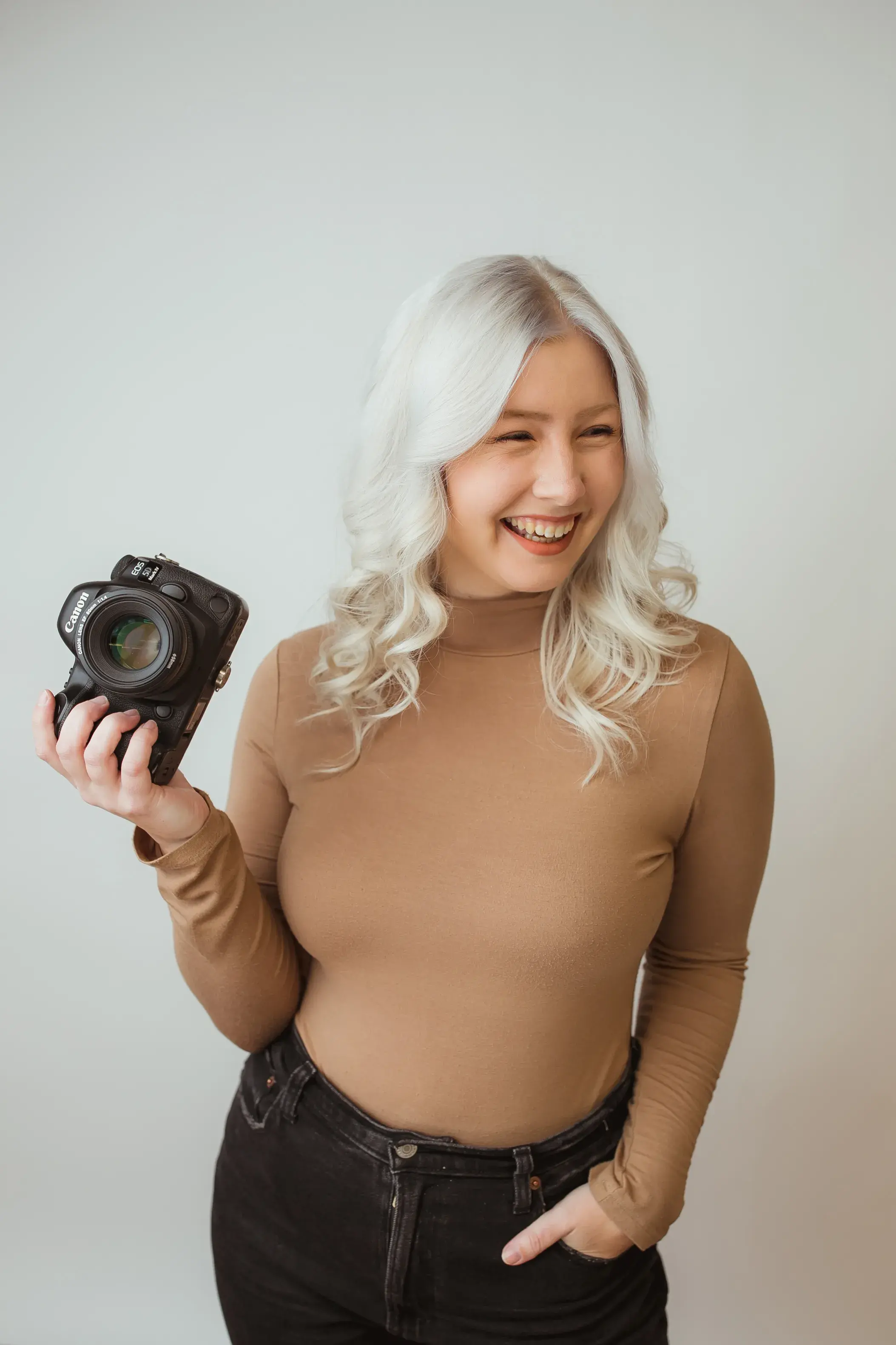 Western Massachusetts photographer smiling while holding a professional camera during a relaxed studio portrait.