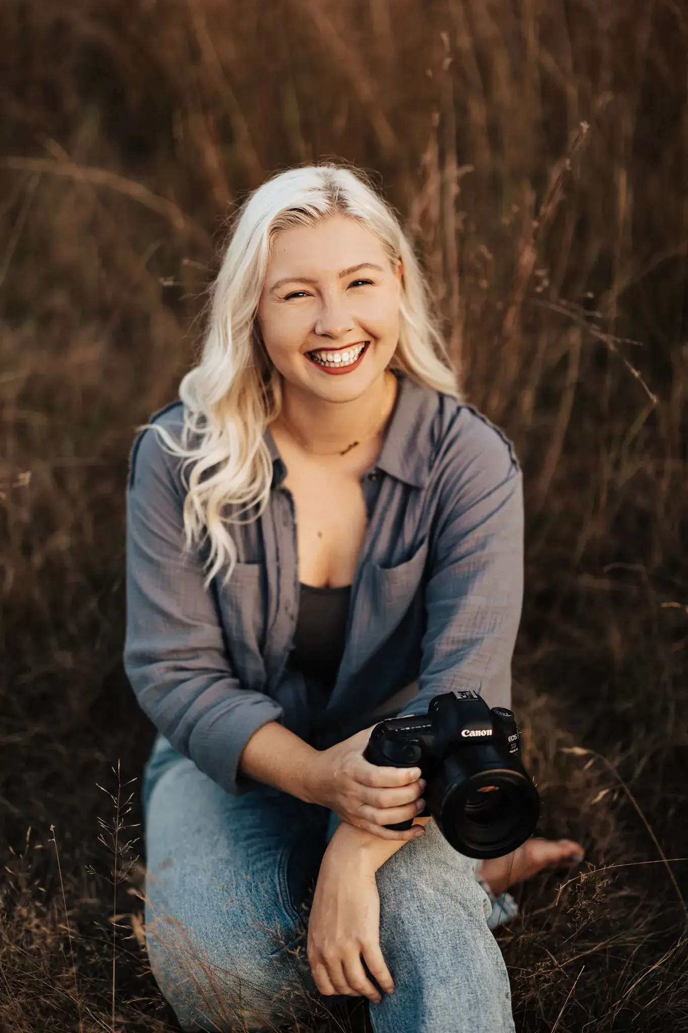 New England wedding photographer based in Massachusetts smiling with her camera during a relaxed outdoor portrait session.