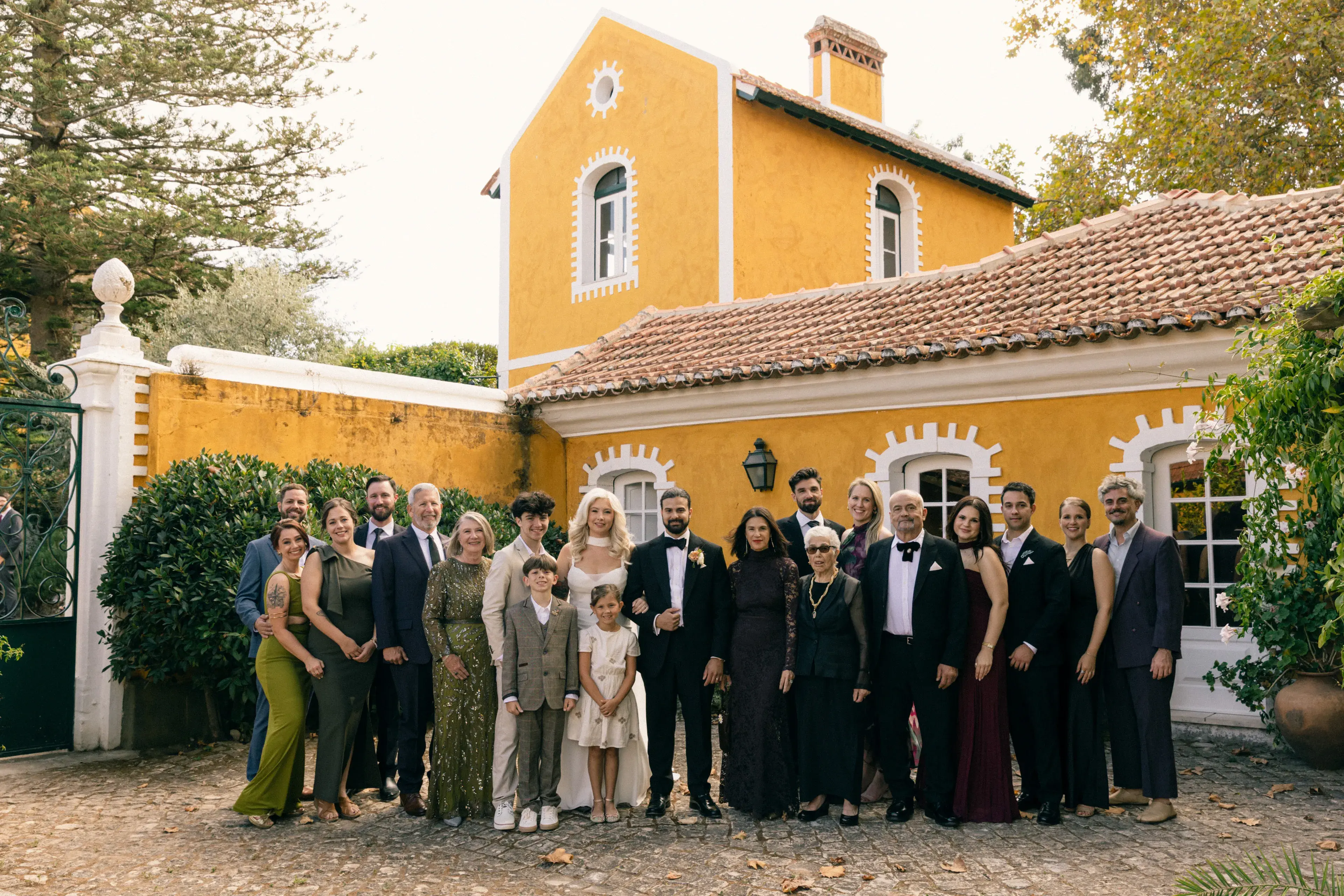 Extended family gathered for a formal portrait during a destination celebration, captured by a New England family photographer in front of a colorful historic estate.