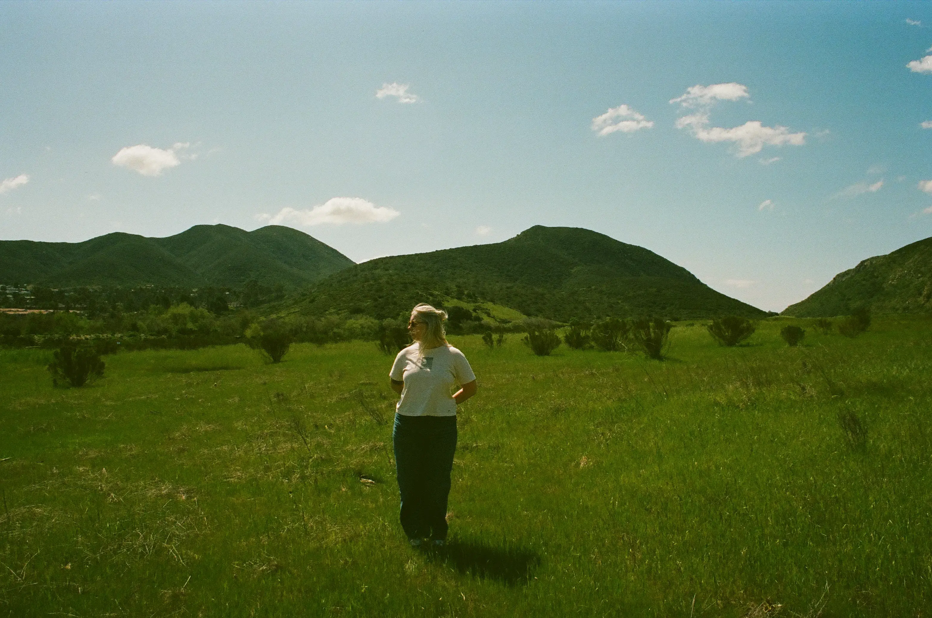 Massachusetts photographer standing in a wide green field with mountain views, captured on film as part of her film and digital photography work.