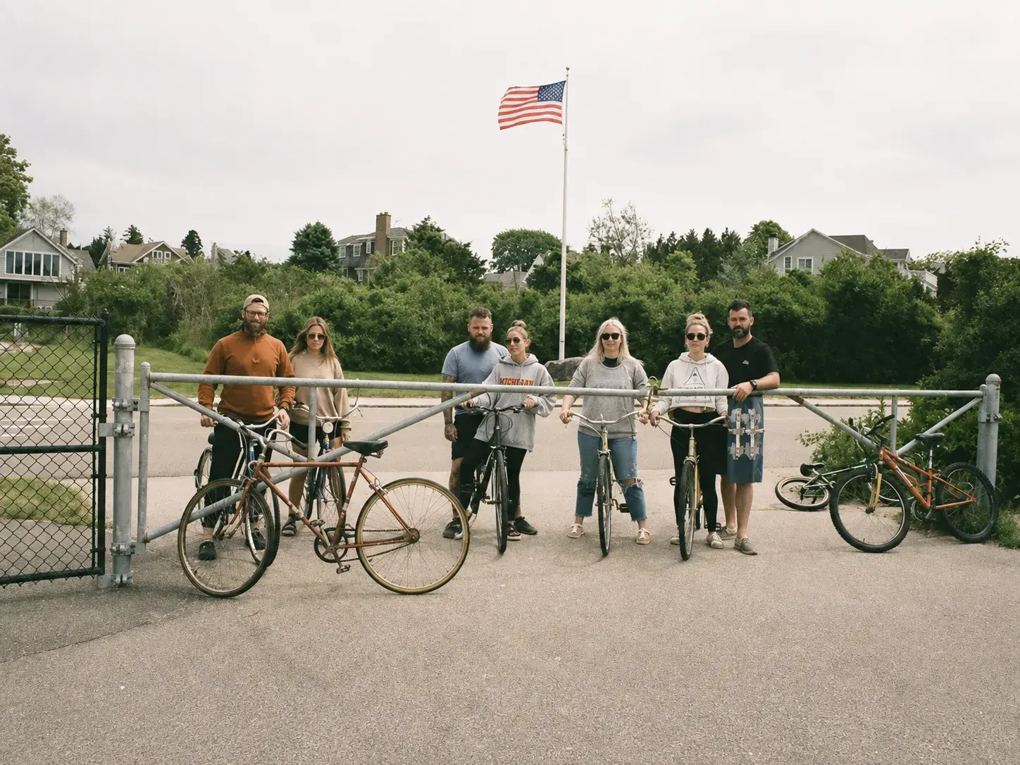 Massachusetts elopement photographer posing with friends and bicycles beneath an American flag during a relaxed outdoor gathering.