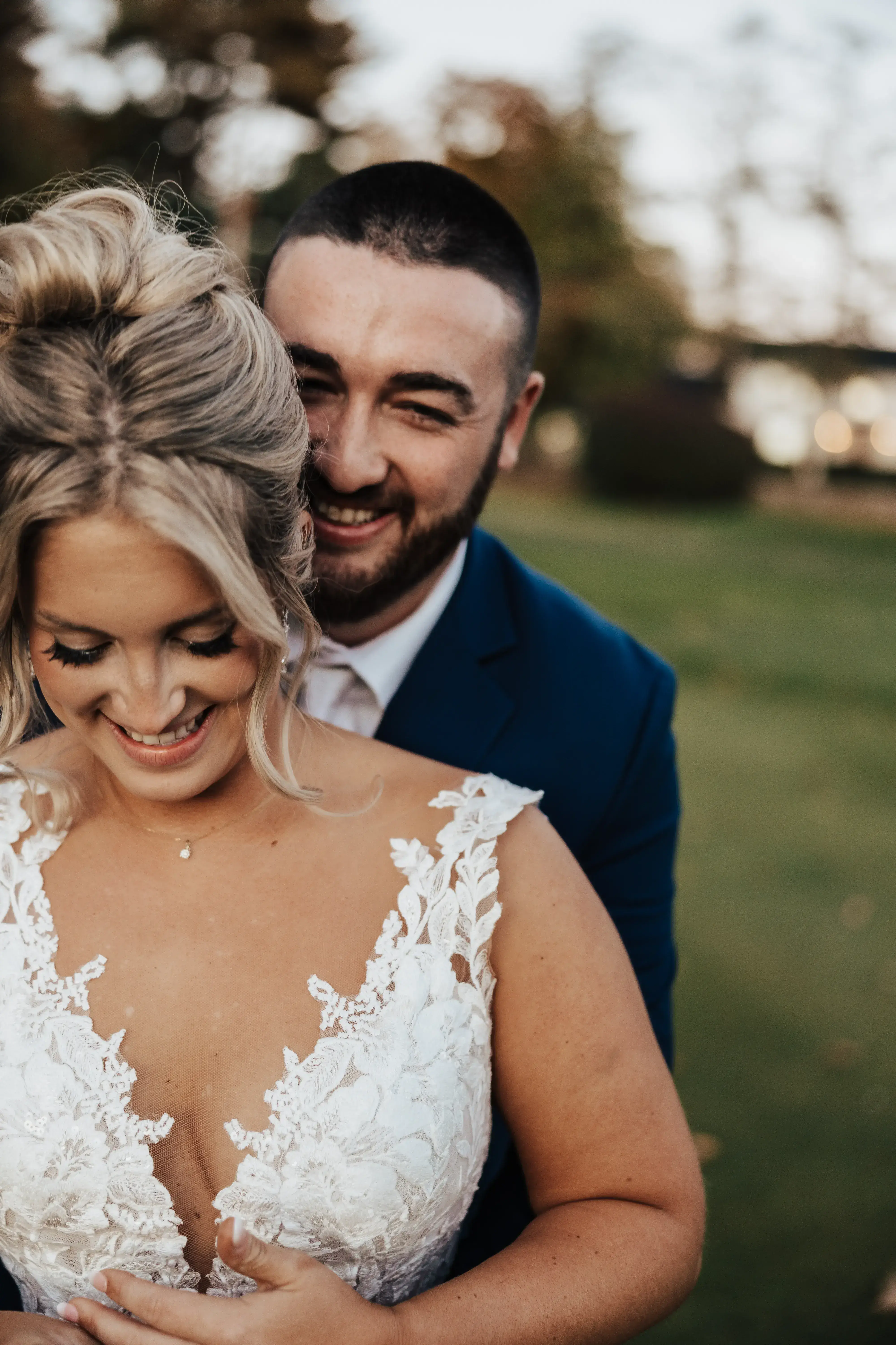 Bride and groom sharing a quiet, joyful moment outdoors after their wedding ceremony, with the groom embracing the bride from behind.