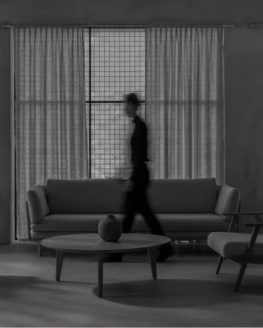Blurred person walking past a modern sofa and coffee table in a minimalistic living room.
