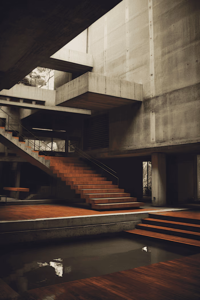 Modern interior with warm wood floating staircase, concrete walls, large window, and gray sofa below.
