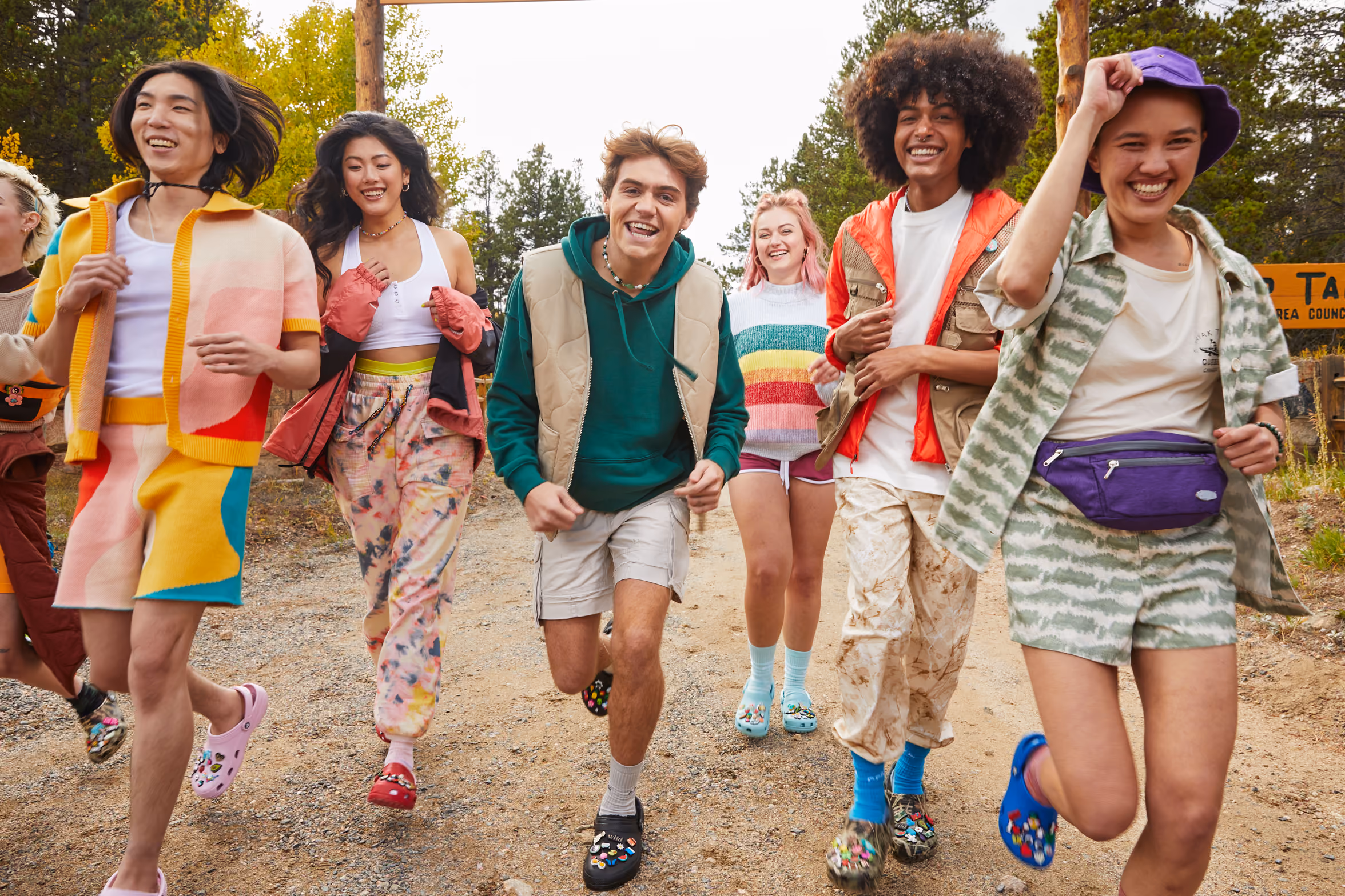 Group of friends running down a campground path wearing Crocs clogs.