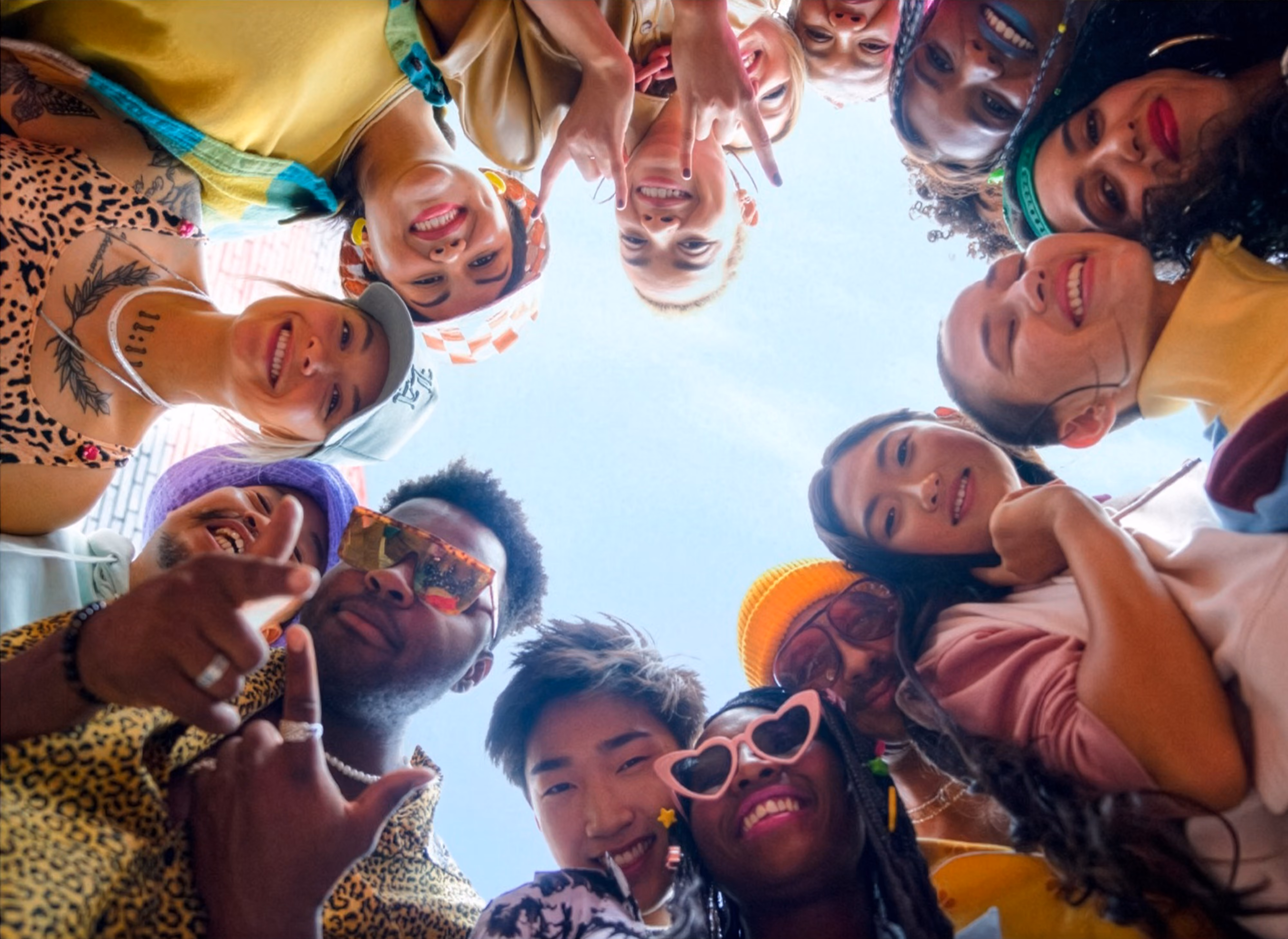 Group of smiling friends forming a circle and looking down at the camera.