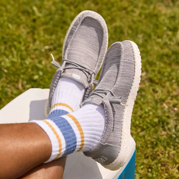 Gray slip-on shoes worn with striped socks outdoors.