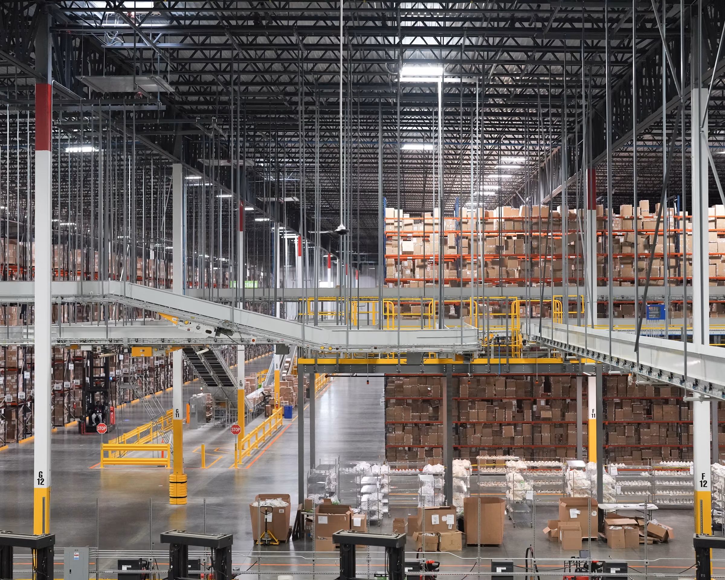 Wide view of a distribution center with shelving, conveyors, and stacked packages.