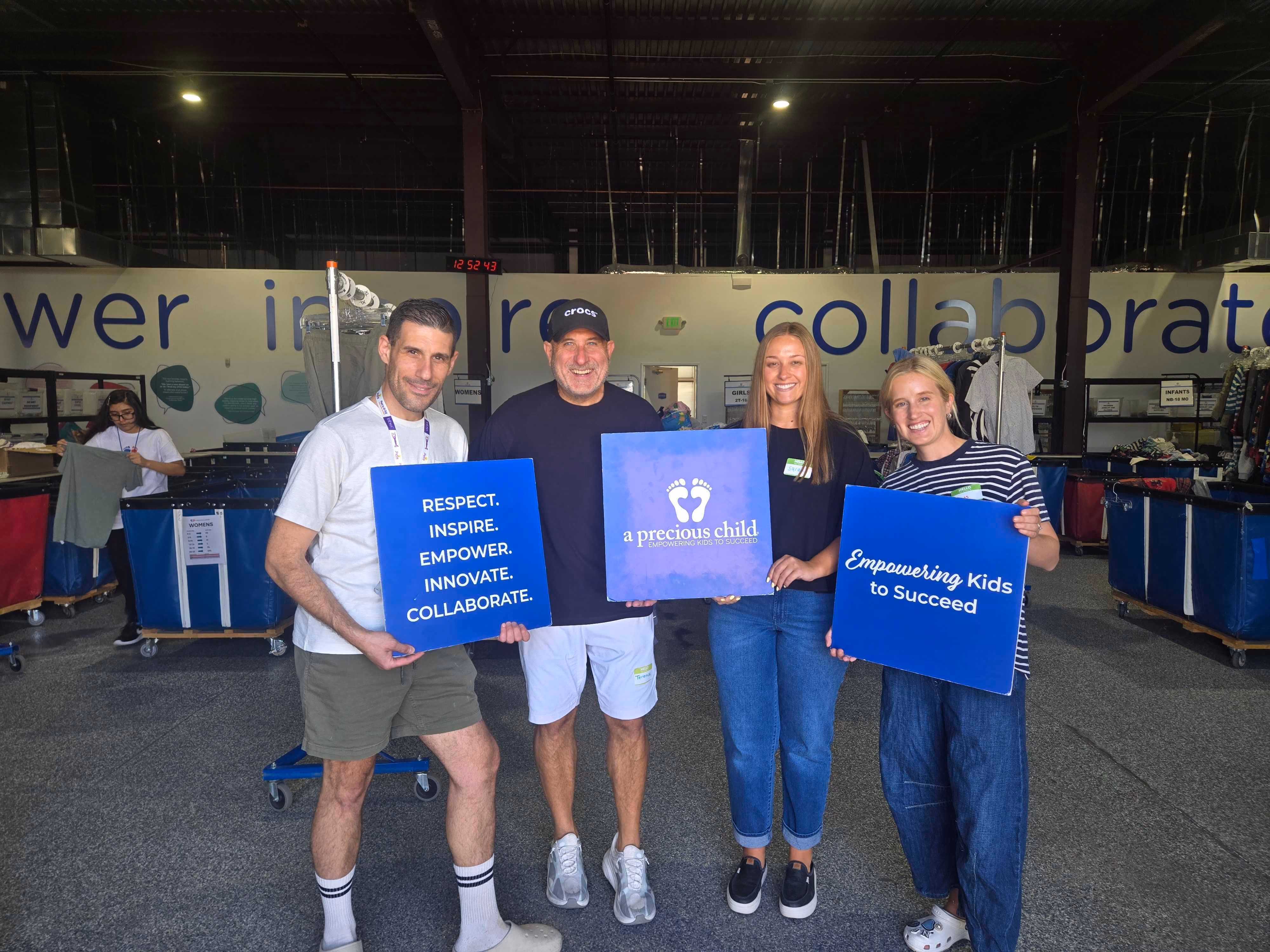 Four Crocs employees holding community volunteer signs at an event.