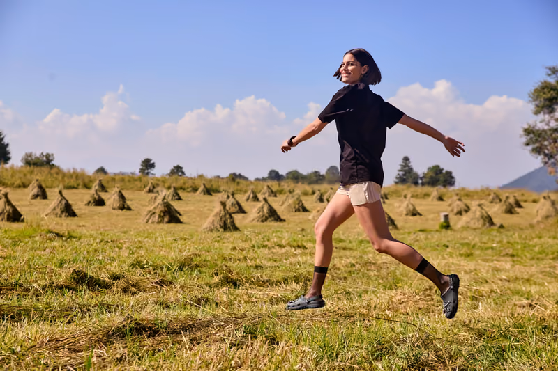 Man running through an open field wearing black slip-on shoes.