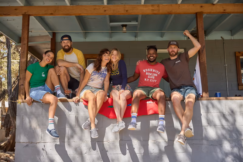 Six friends sitting together on a cabin porch.