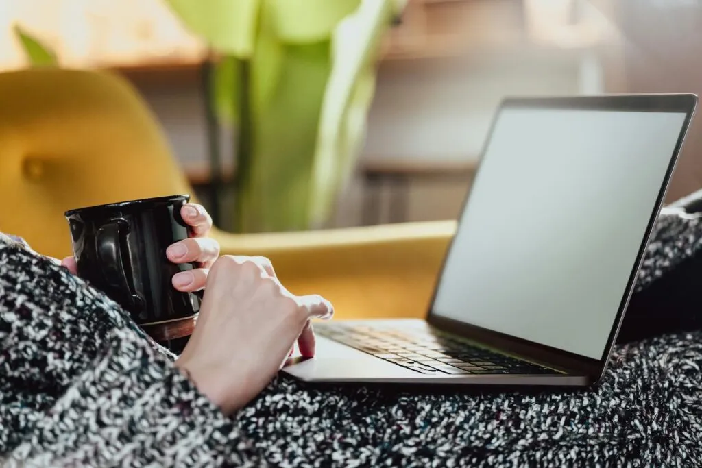 Hands of Woman Holding Cup and Laptop