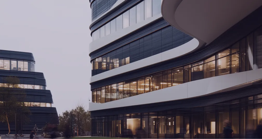 Curved modern office buildings with illuminated windows and blurred people walking outside at dusk.