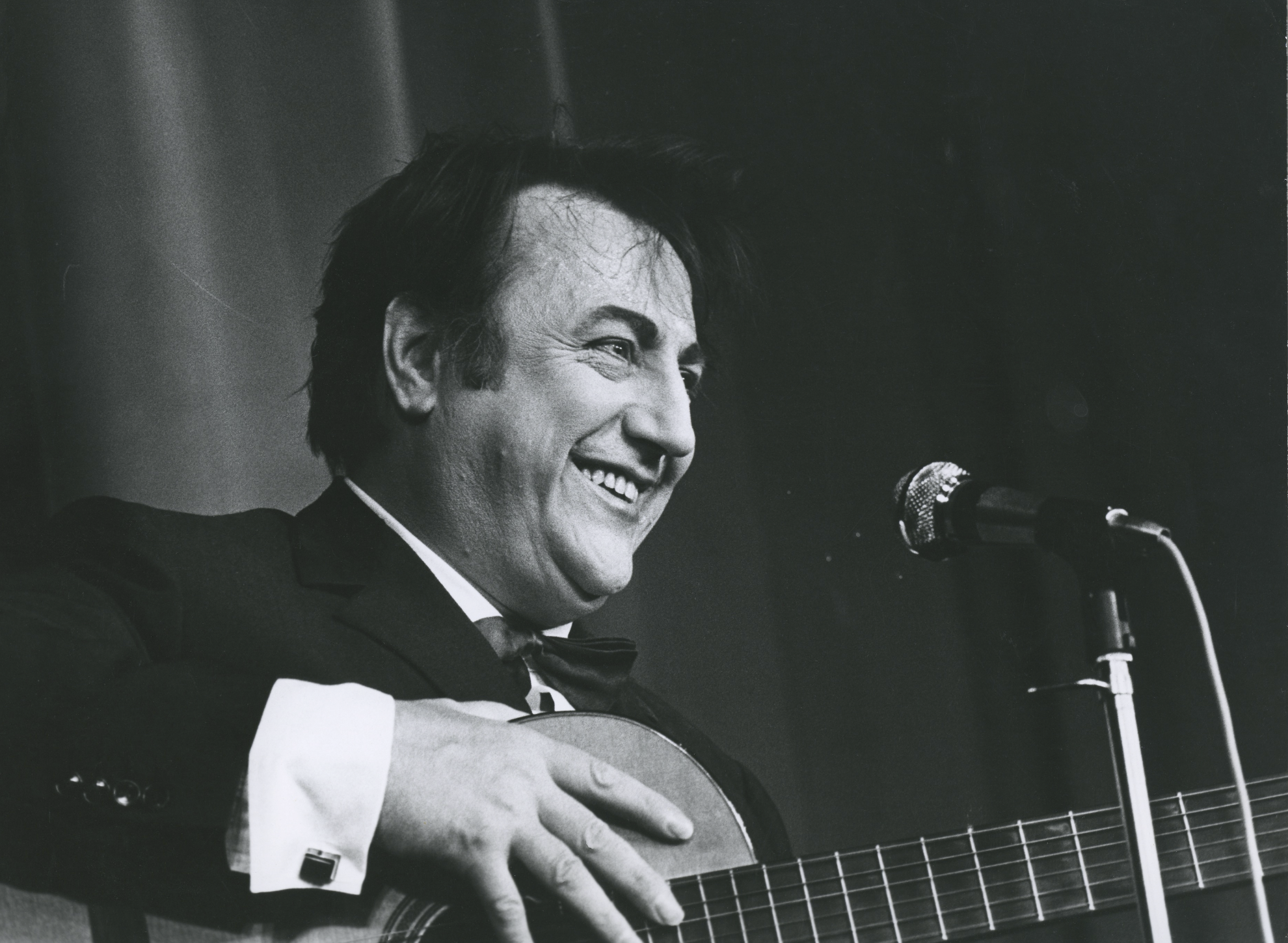 Raymond Devos jouant de la guitare sur scène