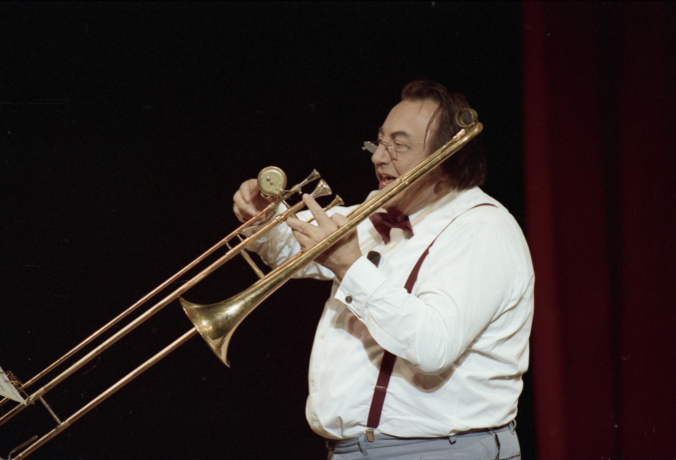 Raymond Devos jouant du trombone sur scène