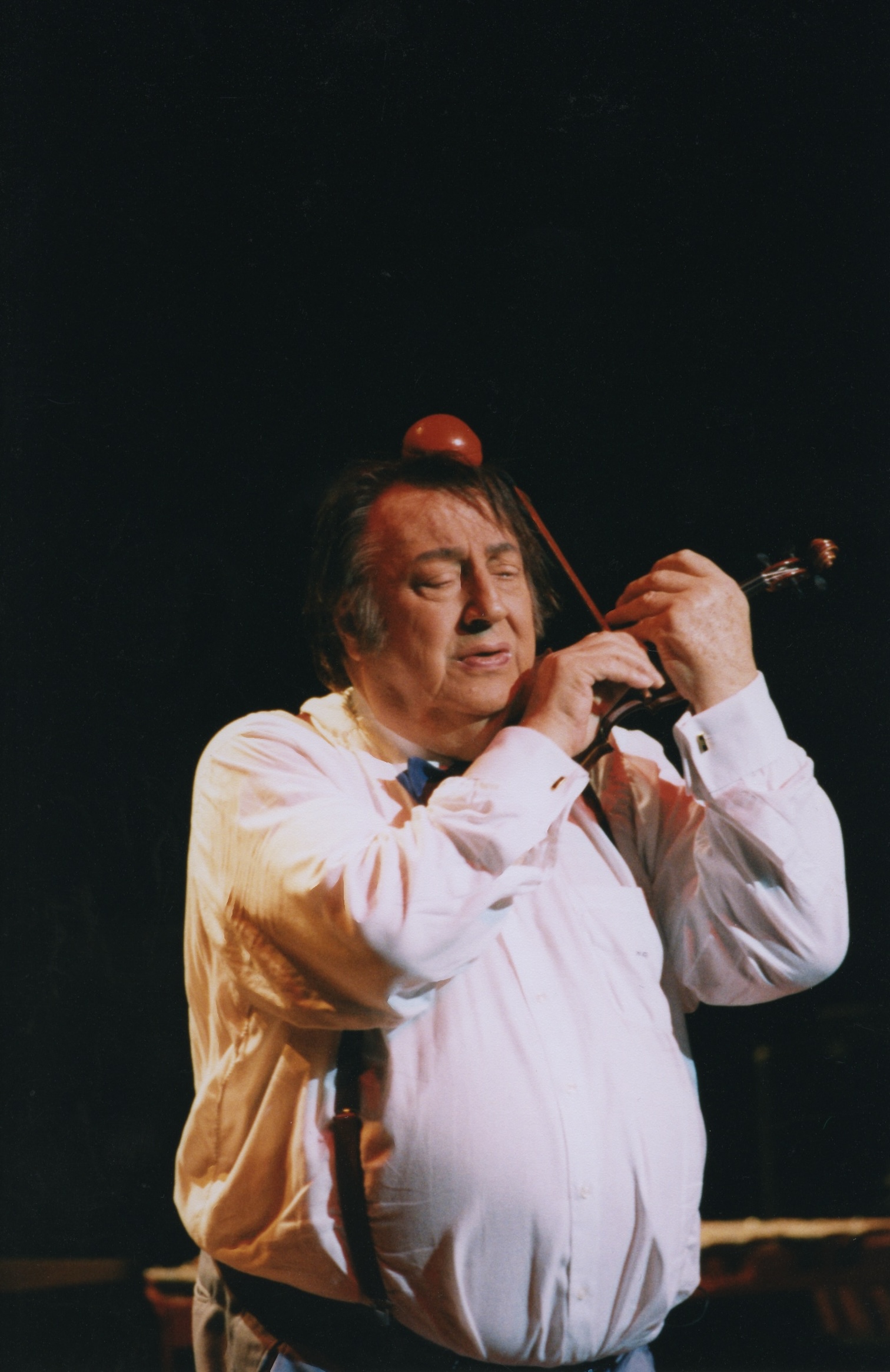 Raymond Devos jouant du violon lors d'un sketch, années 90