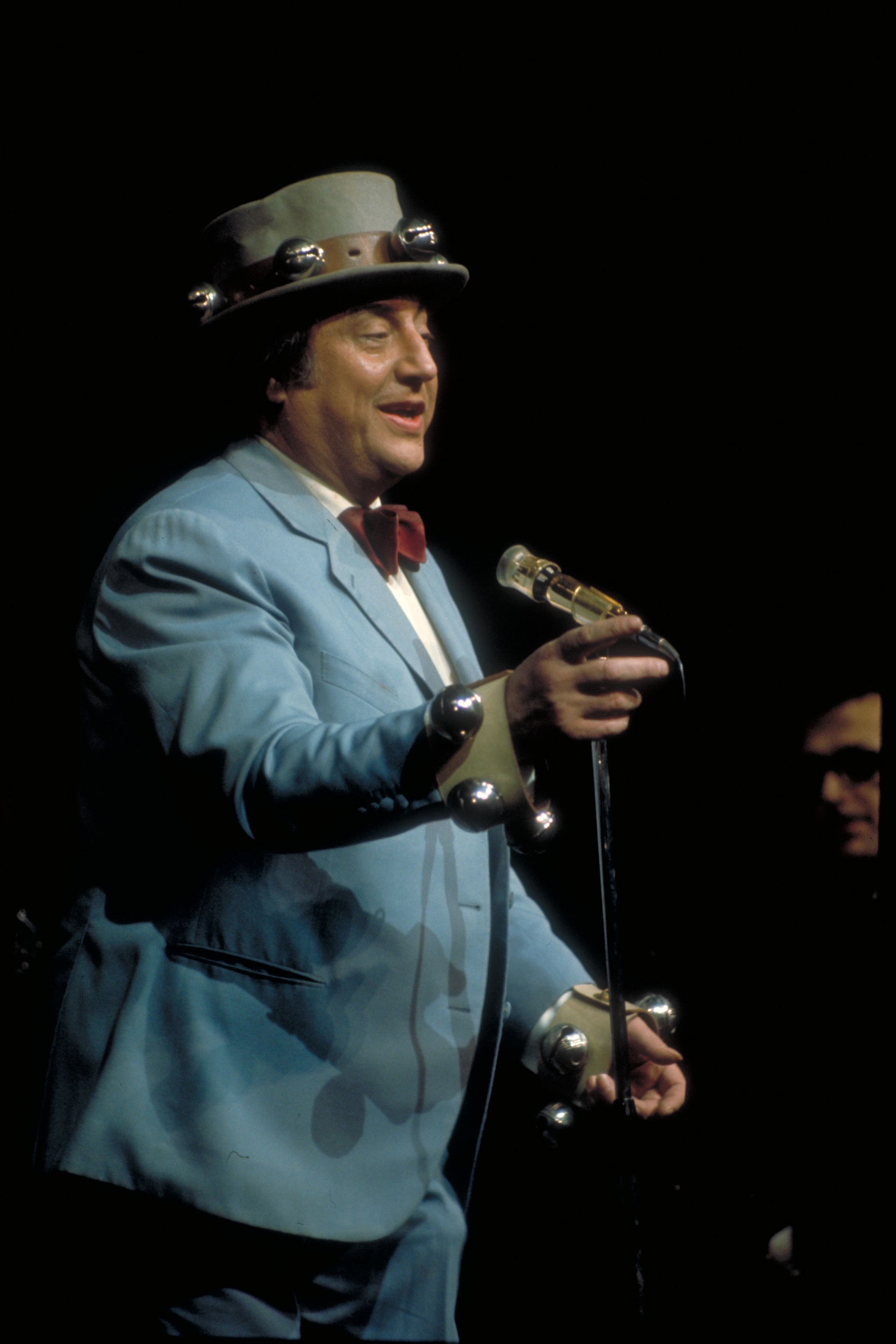 Raymond Devos lors d'un sketch sur scène, coiffé de son chapeau à grelots (crédit photo : Claude Delorme)