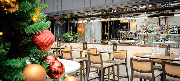 High tables beside the bar at The Grayson, with a decorated Christmas tree